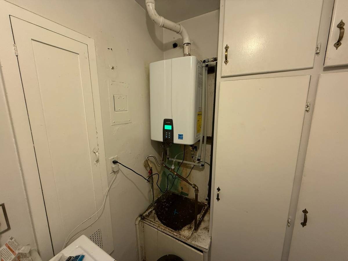 Navien tankless installed in a laundry room with cabinets